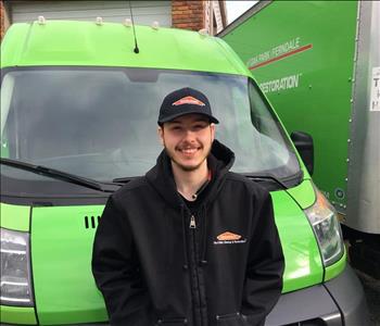 Crew member with SERVPRO hat smiling in front of SERVPRO truck.